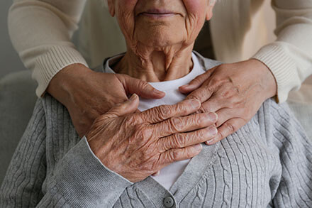 Elderly woman receiving comforting hands-on support.